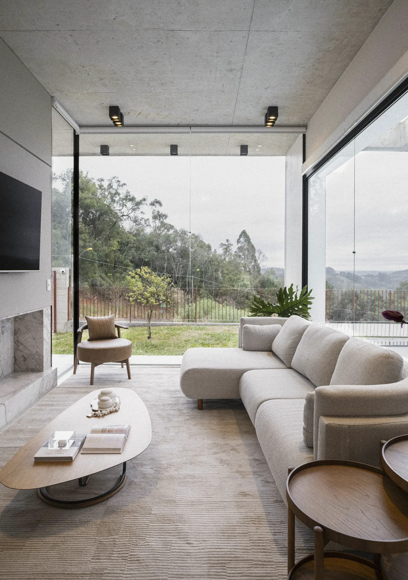 The living room open to the hills, a long pale sofa and an oval walnut table