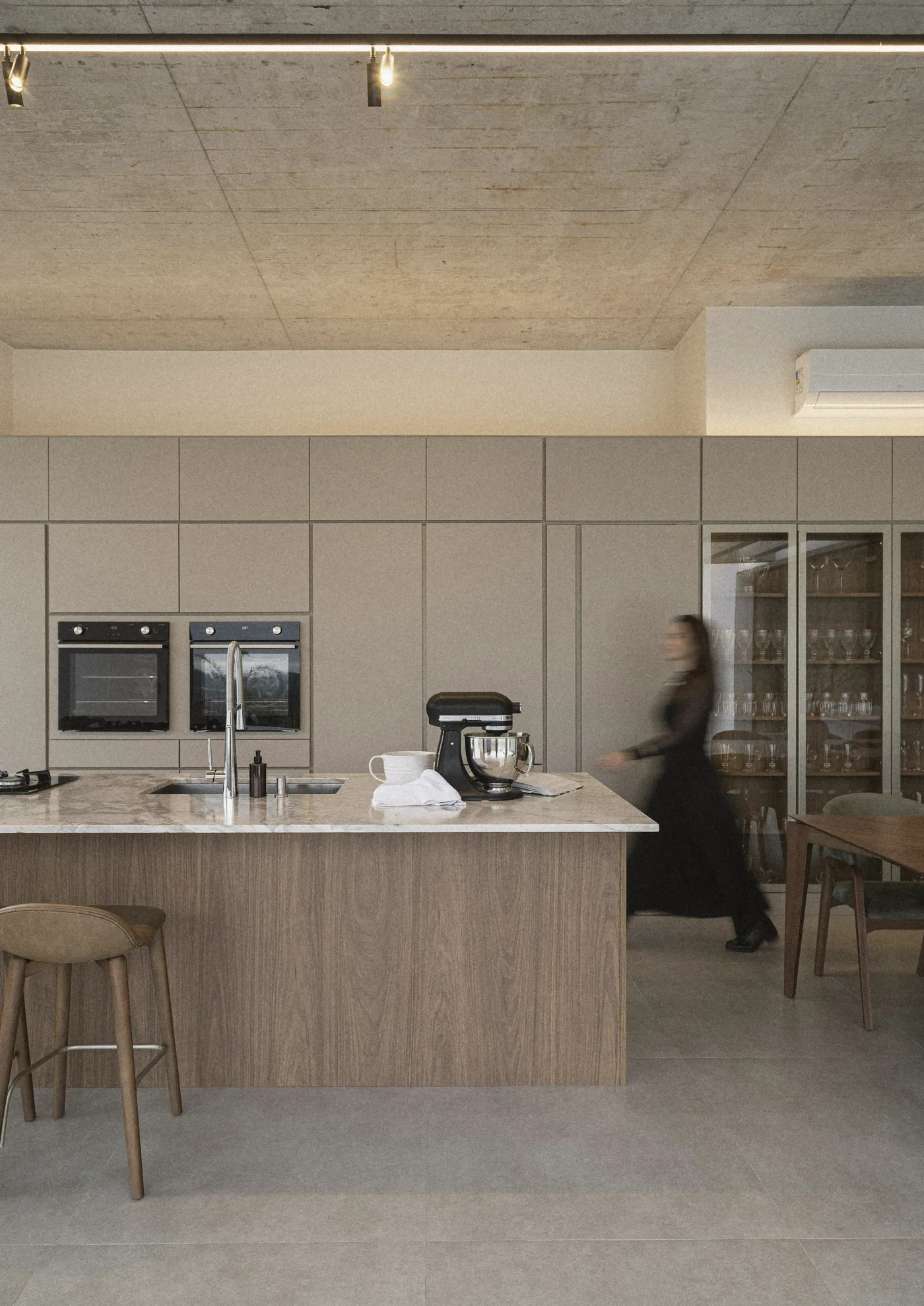 The kitchen, a woman walking past the island